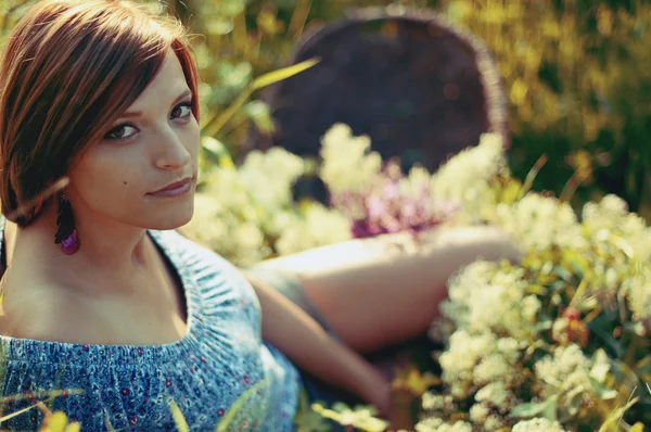 Hermosa mujer sentada en un prado lleno de flores — Foto de Stock