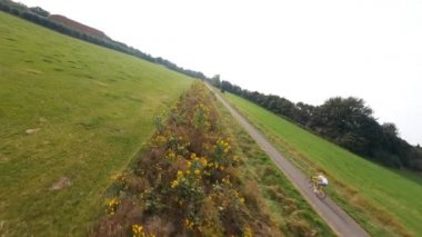 FPV, Hollanda 'da güzel doğa çiçekleri ve çim tarlalarında bisiklet süren bir kadını takip ediyor. Zeeland.