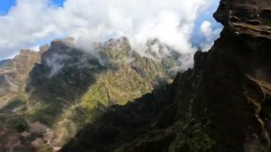 FPV insansız hava aracı ile güzel bir dağ sörfü, Madeira 'daki uçurumlar boyunca yakın uçuş. Aksiyon sporları bulutların arasında uçuyor. Güneşli bir gün.