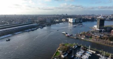 Amsterdam, 8 Aralık 2021, Hollanda. Amsterdam Gözcü Kulesi Film Müzesi ve gün batımında merkez istasyon hava aracı manzaralı feribot..