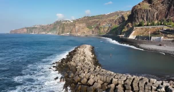 Volcanic coastal beach on Madeira Island Portugal aerial drone view of the water and ocean running along the cliffs and mountains. — Stock Video