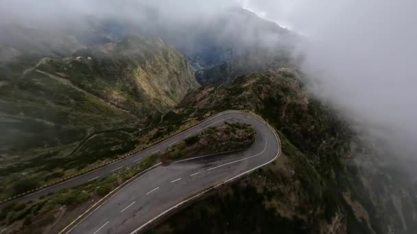 Mountain surfing flying and diving along high cliffs and rocks into a valley. FPV racing drone, Mountain road flying through the clouds. — Stock Video
