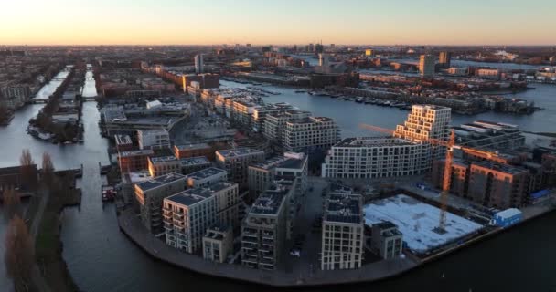 Flybilde over moderne boligbygg i Amsterdam øst ved Cruqius i Nederland. Ved solnedgang i gulltimen. – stockvideo