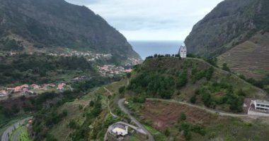Uçurumlar ve dağlarla çevrili küçük bir kilise ve yeşil doğa manzaralı bir köy. Madeira Portekiz 'de.