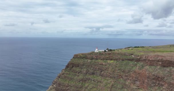 Vista aérea da Madeira pequeno farol ao longo da costa e altas falésias e montanhas ao longo do Oceano Atlântico. — Vídeo de Stock