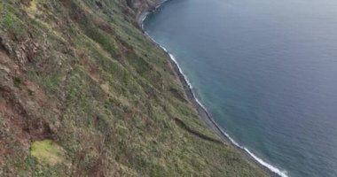 Madeira 'nın kıyı boyunca uzanan küçük deniz feneri, yüksek uçurumlar ve Atlantik Okyanusu boyunca uzanan dağlar..