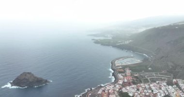 İspanya 'nın Tenerife adasındaki deniz ve kıyı boyunca uzanan küçük bir köyün havadan görünüşü. Tepe tepeleri kayalıkları manzarası.
