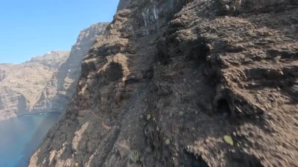 FPV luftklipp av branta klippiga grova klippor dykning flyger längs stenar och stenblock i en robust ocean landskap på en solig destination längs Atlanten i Teneriffa, Spanien, Europa — Stockvideo