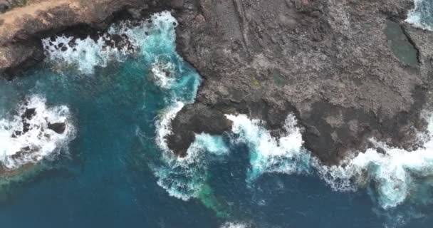 Blue turqoise atlantic ocean sea waves coastline water beating on the rough rocky stone cliffs in a warm summer vacation paradise. Tenerife, Spain, europe. Aerial top down view. looking down. — Stock Video