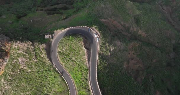 Vista aérea en avión no tripulado de una carretera tortuosa y salvaje en las verdes montañas exuberantes a lo largo de la costa atlántica, un destino soleado de verano, Tenerife, España, Europa. — Vídeos de Stock
