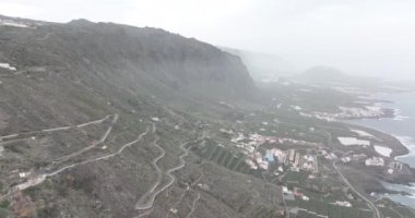 İspanya 'nın Tenerife adasındaki deniz ve kıyı boyunca uzanan küçük bir köyün havadan görünüşü. Tepe tepeleri kayalıkları manzarası.