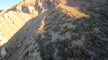Çölde bir FPV insansız hava aracıyla kayalık ve kumlu bir arazi gibi kayalık bir kaya ve dağ sörfü. Dramatik, kaba doğa parkında yakın uçuş..