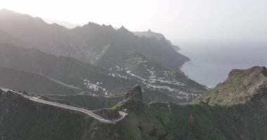 Atlantik kıyısındaki yemyeşil yemyeşil verimli dağlarda vahşi turistik bir yolun insansız hava aracı görüntüsü güneşli bir yaz mevsimi, Tenerife, İspanya, Avrupa.