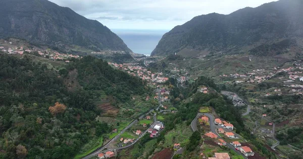 Pequeño pueblo urbano entre altos acantilados en un paisaje verde tropical, mirador aéreo de drones. —  Fotos de Stock