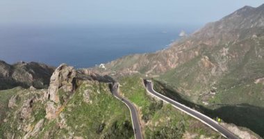 Atlantik kıyısındaki yemyeşil yemyeşil verimli dağlarda vahşi turistik bir yolun insansız hava aracı görüntüsü güneşli bir yaz mevsimi, Tenerife, İspanya, Avrupa.