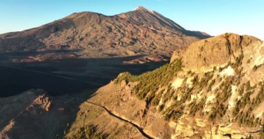 Vahşi bir dağ zirvesi ve bir yol ormanı kayalık volkanik manzarası bulutlarda, Tenerife 'de, İspanya' da, Avrupa 'da altın saat günbatımında..