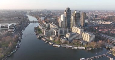 Amsterdam, 23 Mart 2022, Hollanda 'da. Omval ofis binaları. Amstel nehri ve Amstel istasyonu altyapısı boyunca uzanan Amsterdam silueti. Rembrandt Kulesi şehir manzarası.