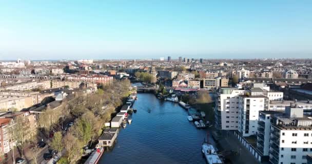 Amsterdam, 26 Mart 2022, Hollanda 'da. Amsterdam 'ın doğusunda Funenkade' de eski bir yel değirmeni De Gooyer. Kanalları olan şehir manzarası. — Stok video
