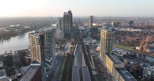 Amsterdamn Amstel kentsel hava aracı görüntülü ulaşım ve kentsel konut kuleleri. Altyapı tren istasyonu iş binaları ve ufuk çizgisi. Su kanalı. — Stok video