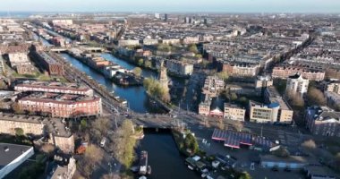 Amsterdam, 26 Mart 2022, Hollanda 'da. Amsterdam 'ın doğusunda Funenkade' de eski bir yel değirmeni De Gooyer. Kanalları olan şehir manzarası.