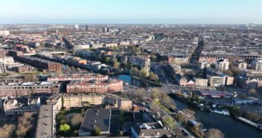 Amsterdam, 26 Mart 2022, Hollanda 'da. Amsterdam 'ın doğusunda Funenkade' de eski bir yel değirmeni De Gooyer. Kanalları olan şehir manzarası.