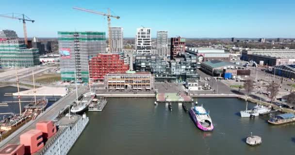 Amsterdam, 19 marzo 2022, Paesi Bassi. Traghetto NDSM in arrivo moderno cantiere navale industriale e zona residenziale alla moda. GVB Ijveer arrivo dei passeggeri del trasporto pubblico vista aerea drone. — Video Stock