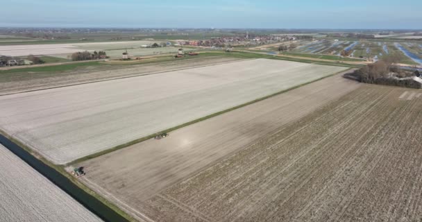 Exploitation d'une activité de labour de tracteurs par un agriculteur dans un tracteur au printemps. Vue aérienne par drone d'un travailleur cultivant un champ et des terres agricoles aux Pays-Bas. — Video