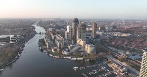 Амстердам, 23 марта 2022 года, Нидерланды. Омвальные офисные здания. Воздушное пространство вдоль реки и инфраструктура Амстердамского вокзала - городской деловой район. Башня Рембрандта. — стоковое видео