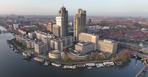 Амстердам, 23 марта 2022 года, Нидерланды. Омвальные офисные здания. Воздушное пространство вдоль реки и инфраструктура Амстердамского вокзала - городской деловой район. Башня Рембрандта. — стоковое видео