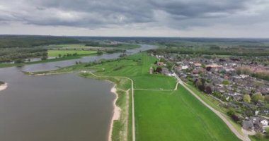 Hollanda 'nın Gelderland eyaletindeki Lower Rhine nehri kıyısındaki Heteren köyü nehrin hava aracı görüntüsü ve su boyunca binalar...