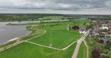 Hollanda 'nın Gelderland eyaletindeki Lower Rhine nehri kıyısındaki Heteren köyü nehrin hava aracı görüntüsü ve su boyunca binalar...
