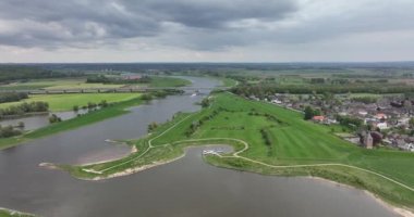 Hollanda 'nın Gelderland eyaletindeki Lower Rhine nehri kıyısındaki Heteren köyü nehrin hava aracı görüntüsü ve su boyunca binalar...