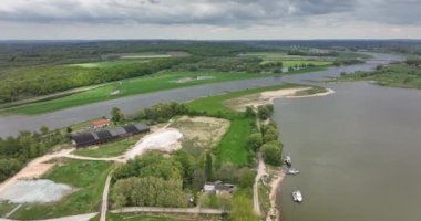Hollanda 'nın Gelderland eyaletindeki Lower Rhine nehri kıyısındaki Heteren köyü nehrin hava aracı görüntüsü ve su boyunca binalar...
