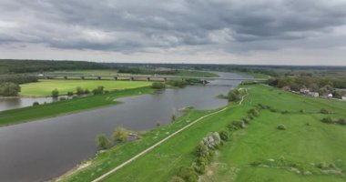 Hollanda 'nın Gelderland eyaletindeki Lower Rhine nehri kıyısındaki Heteren köyü nehrin hava aracı görüntüsü ve su boyunca binalar...