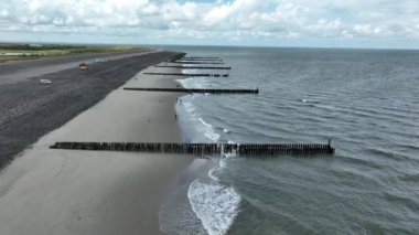 Hollanda Hollanda 'nın kumlu sahil sahili dramatik sahili kıyısı. Su hattı ve kırılan tahta direkler Zeeland 'deki Noordzee boyunca uzanır..