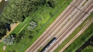 Utrecht, 1st of July 2022, The Netherlands. NS train Nederlandse Spoorwegen FPV drone high speed follow through a grassland landscape. Sustainable travel mobility.