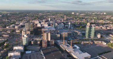 Utrecht silueti ve merkez istasyon toplu taşıma altyapısı ve iş bölgesi. Havadan insansız hava aracı görüntüsü. Şehir merkezindeki yüksek binalar ve kuleler.