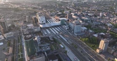 Utrecht silueti ve merkez istasyon toplu taşıma altyapısı ve iş bölgesi. Havadan insansız hava aracı görüntüsü. Şehir merkezindeki yüksek binalar ve kuleler.