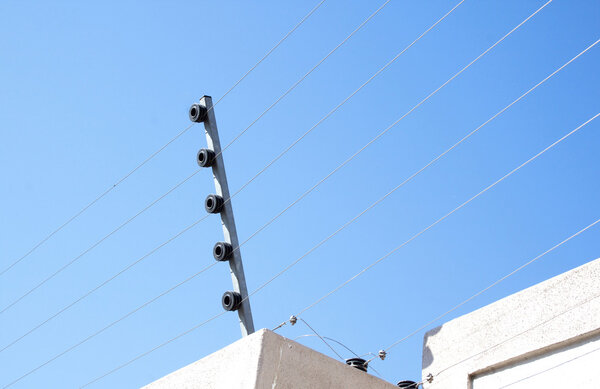 Вид на электрический забор, установленный на бетонной стене
