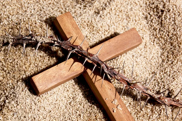 Fechar a cruz de madeira e espinhos no fundo de areia — Fotografia de Stock