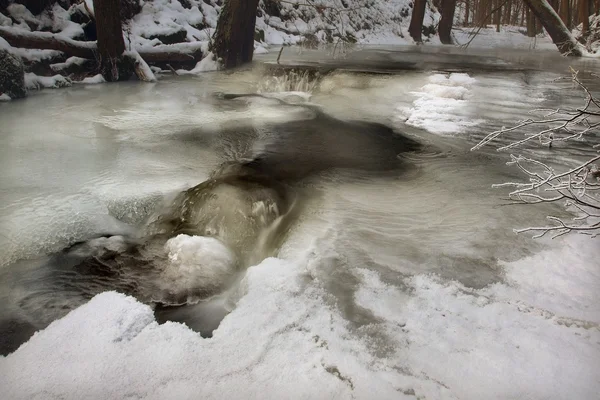 Vista notturna invernale su ghiaccioli e massi ghiacciati nel torrente . — Foto Stock