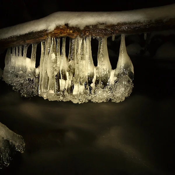 Nacht winter weergeven ijspegels en het ijzige rotsen in de stream. — Stockfoto