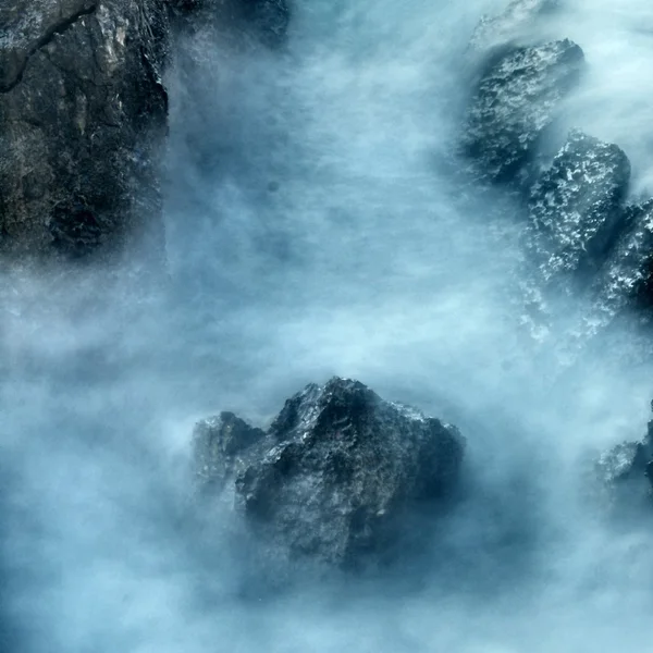 Scherpe rif in blauwe troubled water, zout spray hierboven, lawaaierige golven. — Stockfoto