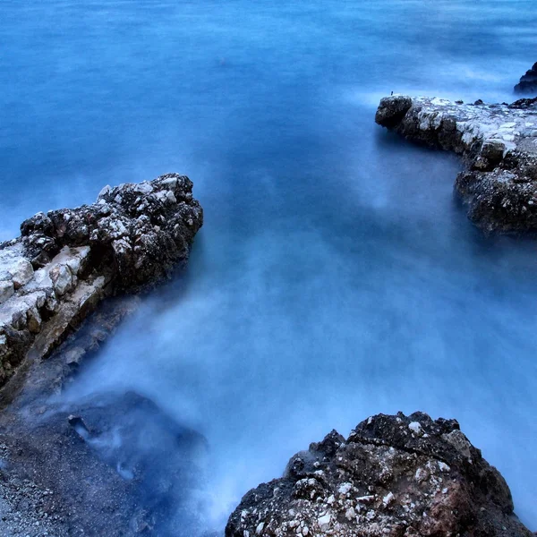 Recife afiado em água azul conturbada, spray de sal acima, ondas barulhentas . — Fotografia de Stock