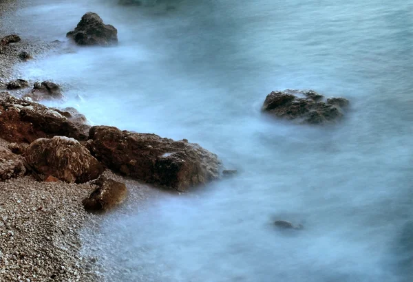 Sharp reef in blue troubled water, salt spray above, noisy waves. — Stock Photo, Image