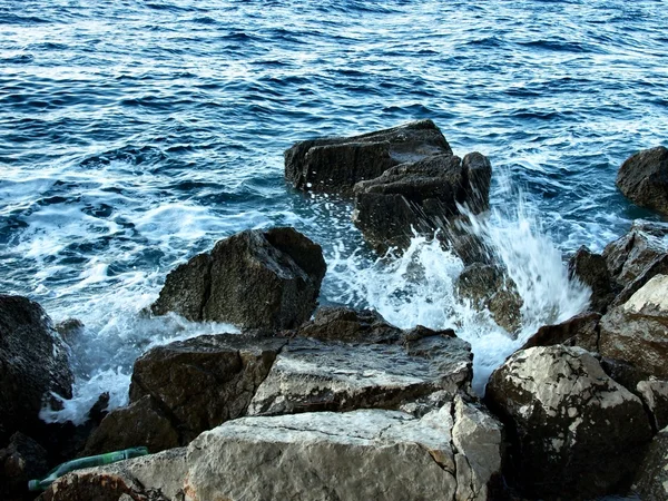 Récif aigu dans l'eau bleue trouble, embruns salins au-dessus, vagues bruyantes . — Photo