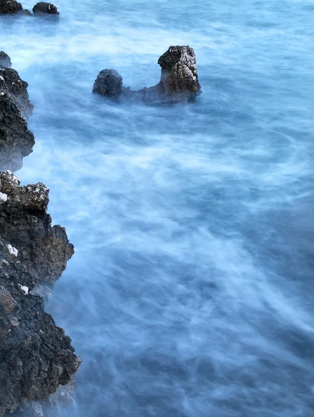 Felsen im blauen, unruhigen Wasser. — Stockfoto