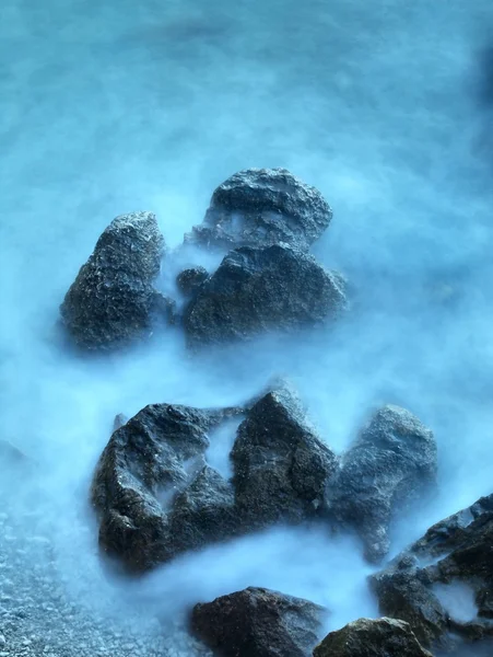 Rocks in blue troubled watter. — Stock Photo, Image