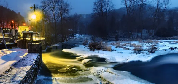 Nuit d'hiver sous le barrage. Réflexion des lampes dans la glace, la glace et l'eau froide . — Photo