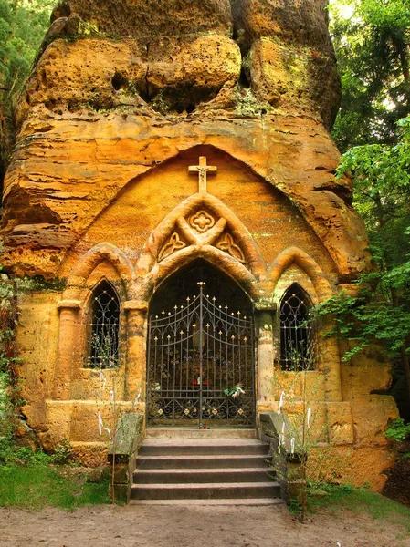 Small village chapel hewed into sandstone block. Small statue of Madonna in hewed cave, flower at Madonnas legs. — Stock Photo, Image